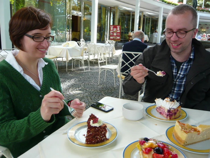 a man and woman at a table with plates of cake