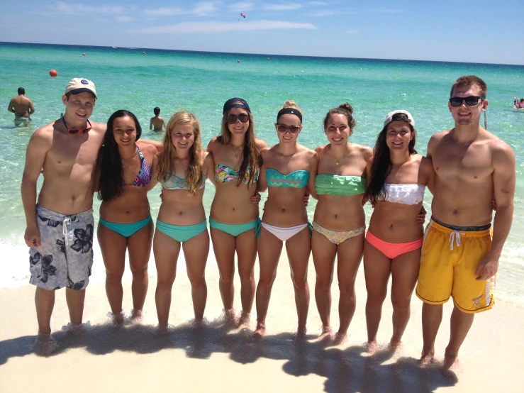 a group of people are in swimsuits standing on the beach