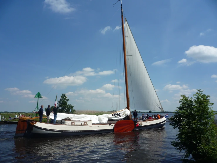 a sailboat on the water with people standing on it