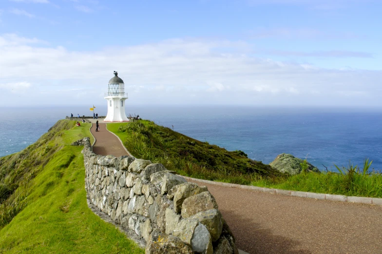 a lighthouse next to a stone wall and road