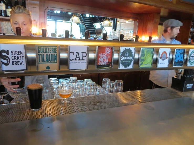 a man at a bar behind the bar making beers