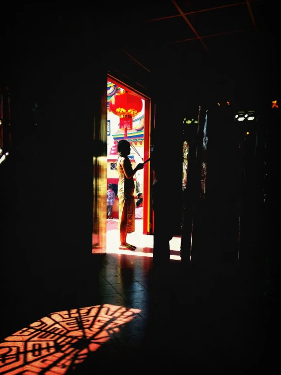 silhouette in a dark hallway with open door, woman with umbrella behind