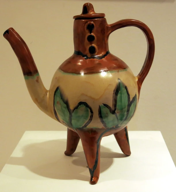 a ceramic tea pot with painted details on it