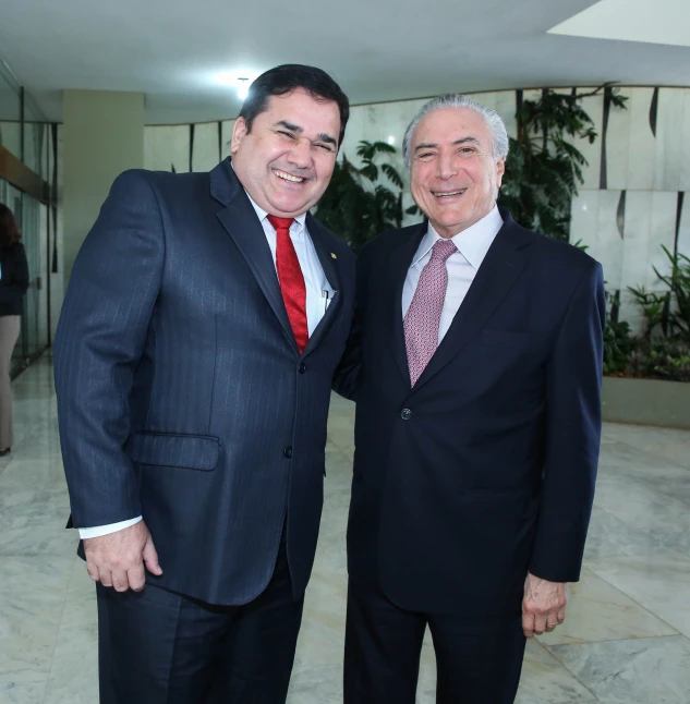 two men in suits smiling for the camera