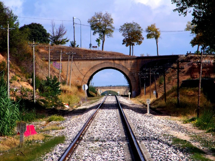 there is a train track going under an old bridge