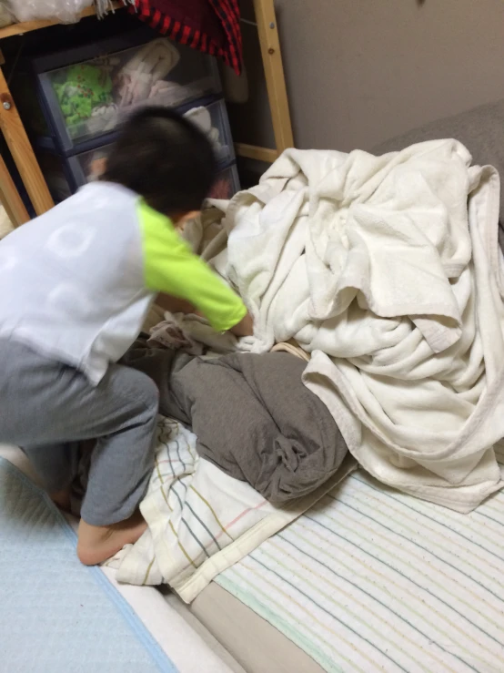 a young child laying on top of a bed with sheets on it