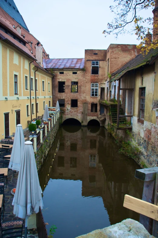 looking down a canal in an alley with tables and umbrellas