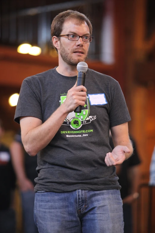 a man holding a microphone standing up in front of a crowd