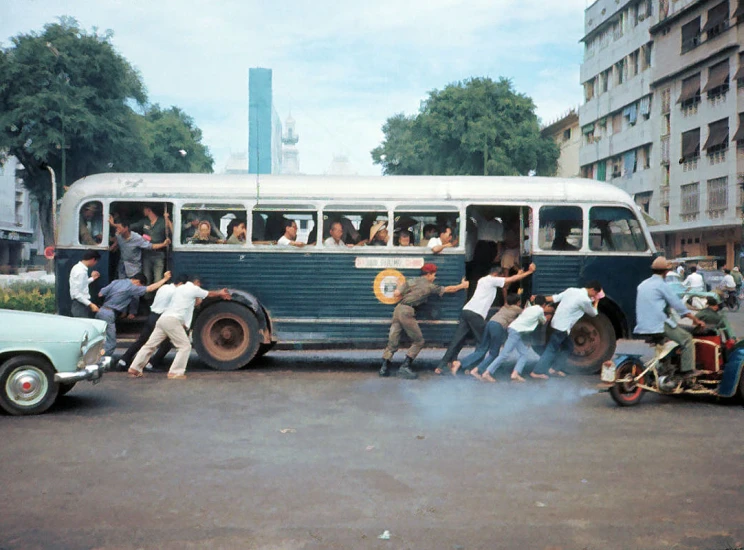 several people standing outside the back of an old bus