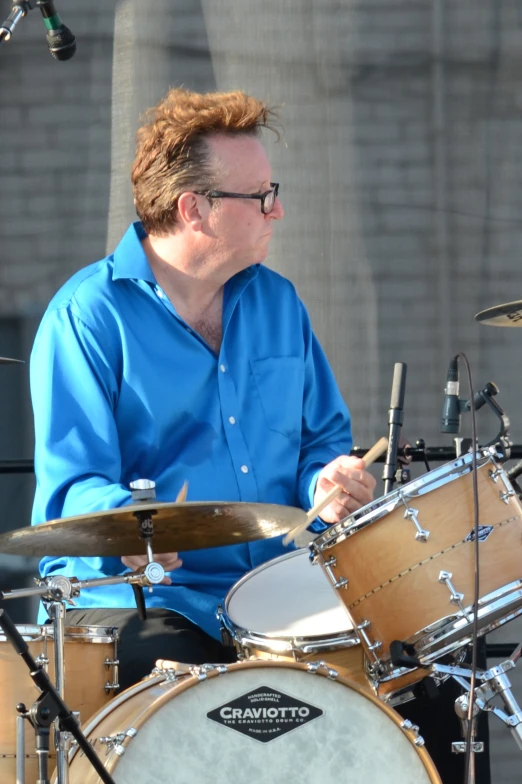 a man sitting down playing drums in front of some microphones