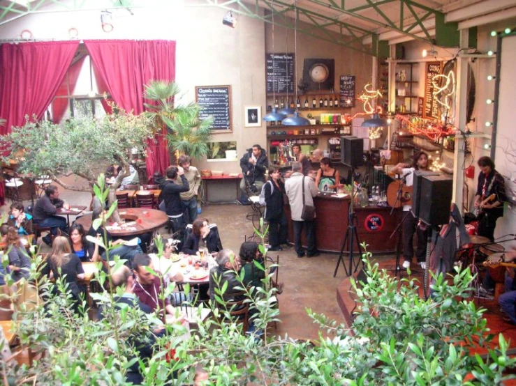 an open air cafe with people sitting and standing