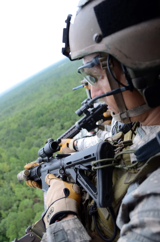 military men holding their guns as they look out from a window