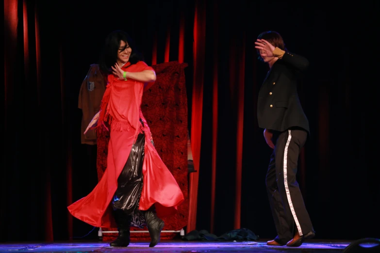 a woman standing on a runway while another man walks by behind her