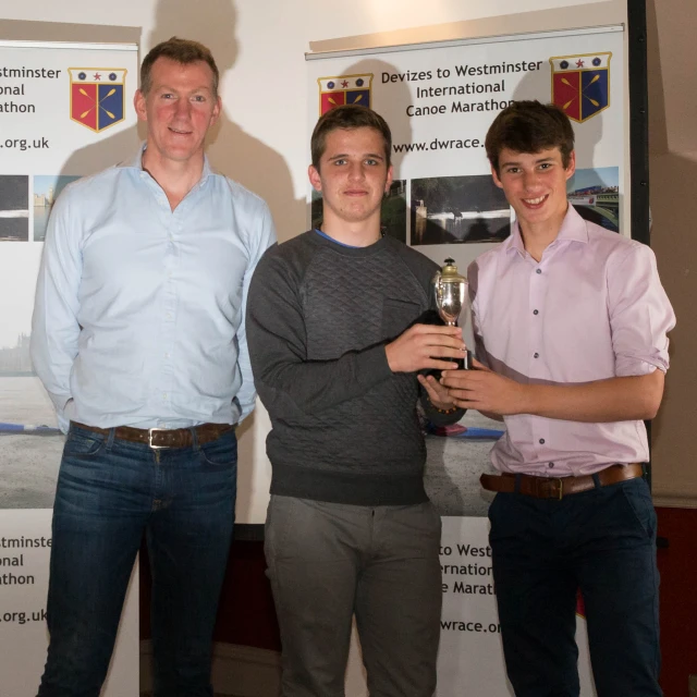 three young men are holding an award in a pose