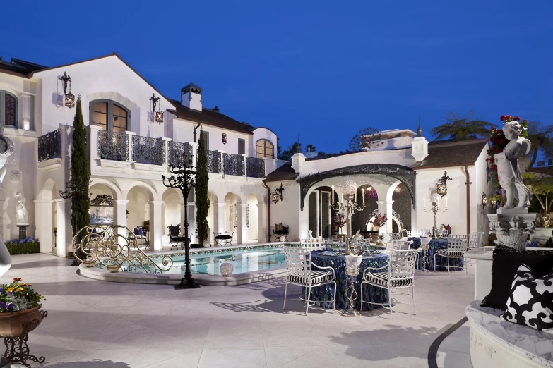 a white building with lots of tables and chairs outside at night