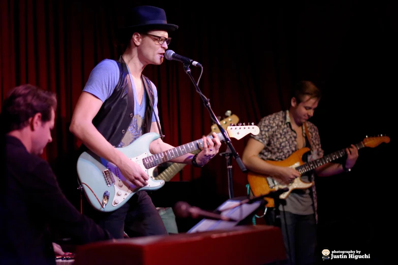 two musicians perform with guitars in front of microphones