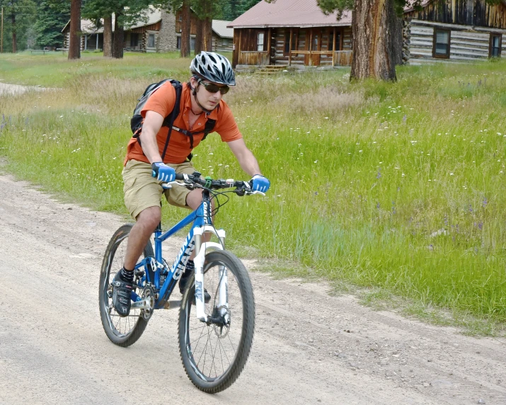 the man in an orange shirt is riding his bike