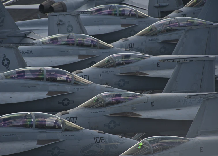 many military jets sit parked in a field