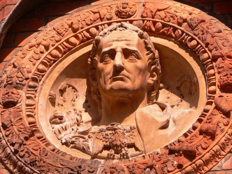 a stone head on a red wall has flowers growing in it