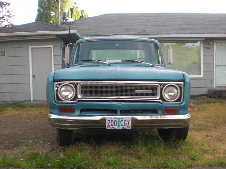 an old blue truck is parked in front of a house