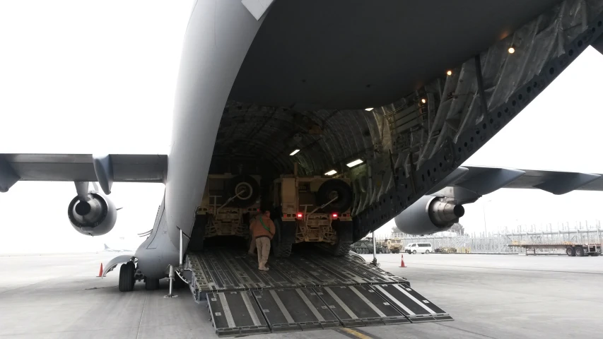 a man loading cargo into the back of a military plane