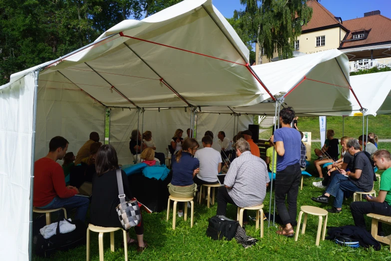 several people sitting on chairs under a tent