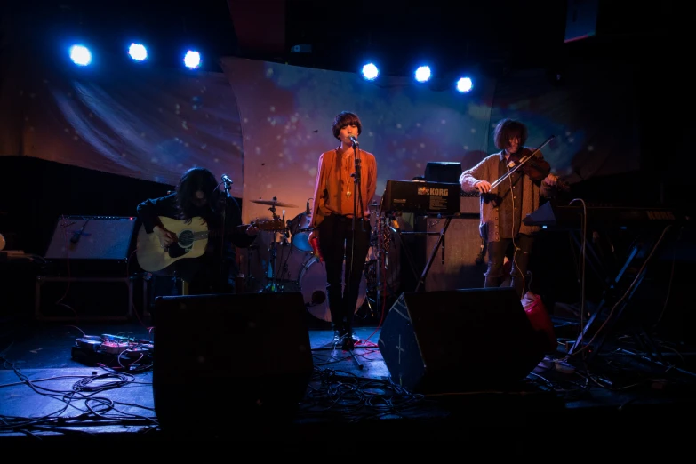 a group of men stand on stage playing musical instruments