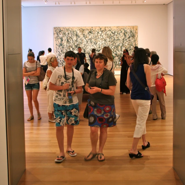 two women stand at an art gallery with people in the background