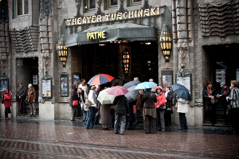 a crowd of people standing outside a building holding umbrellas