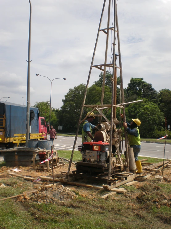 two men are fixing a wooden structure next to the road