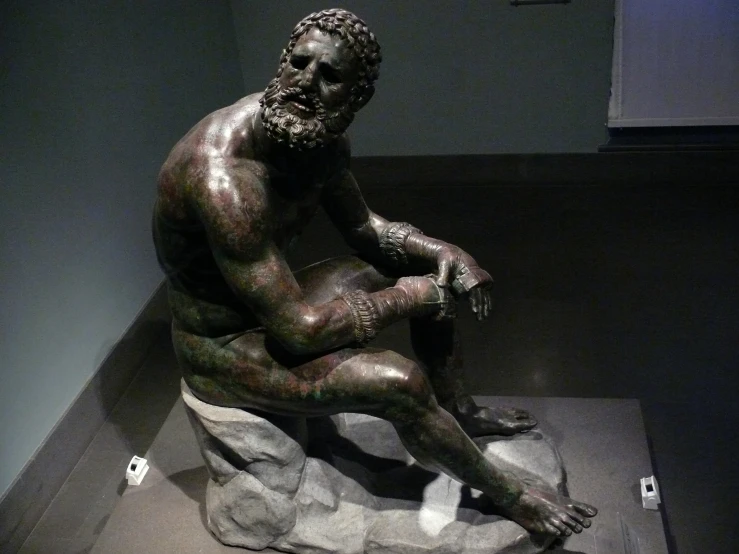 a bronze statue of a man sitting on a rock