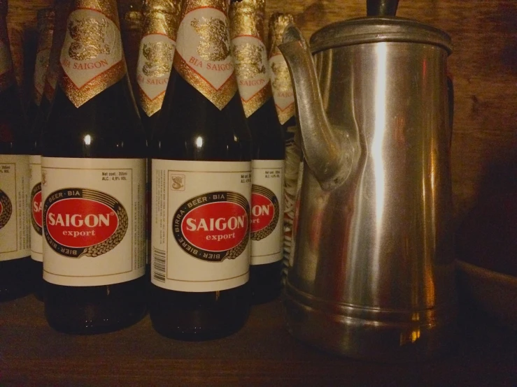 six bottles on a wooden shelf with an english kettle