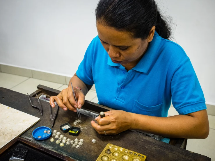 a woman in blue shirt working on an electronic device