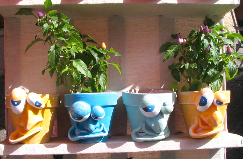 several flower pots sitting on a shelf are painted to look like monsters
