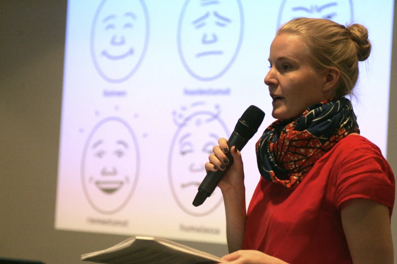 a woman stands in front of a projector while talking