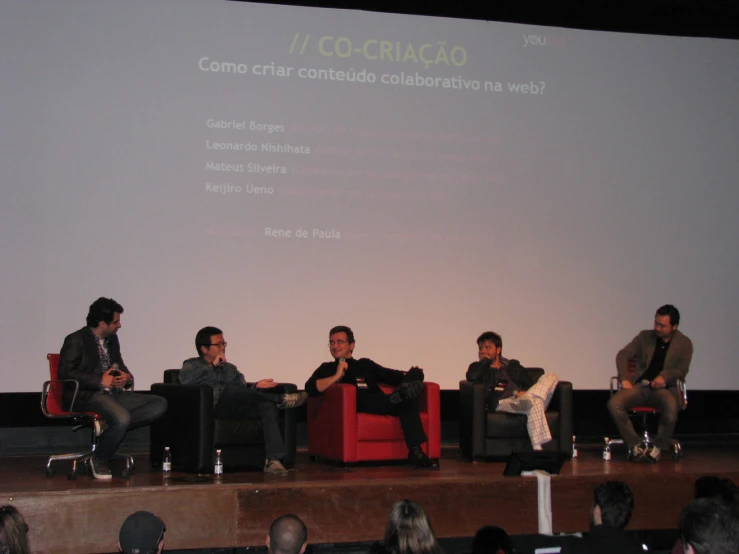 four men are on chairs while speaking