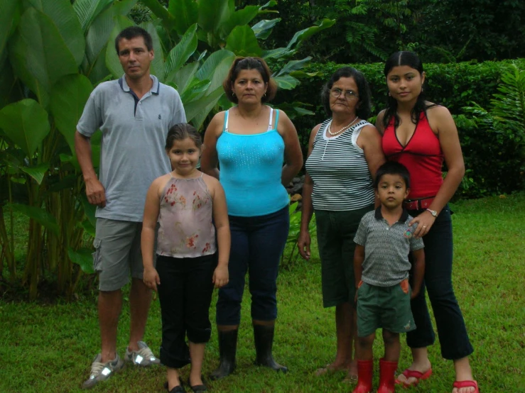 a man and woman with two children in front of a banana tree