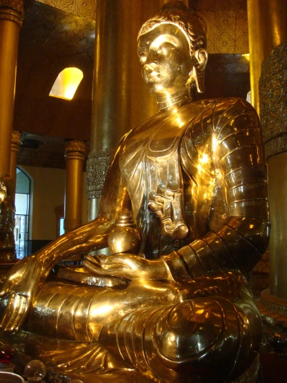 a golden statue is sitting among gold pillars