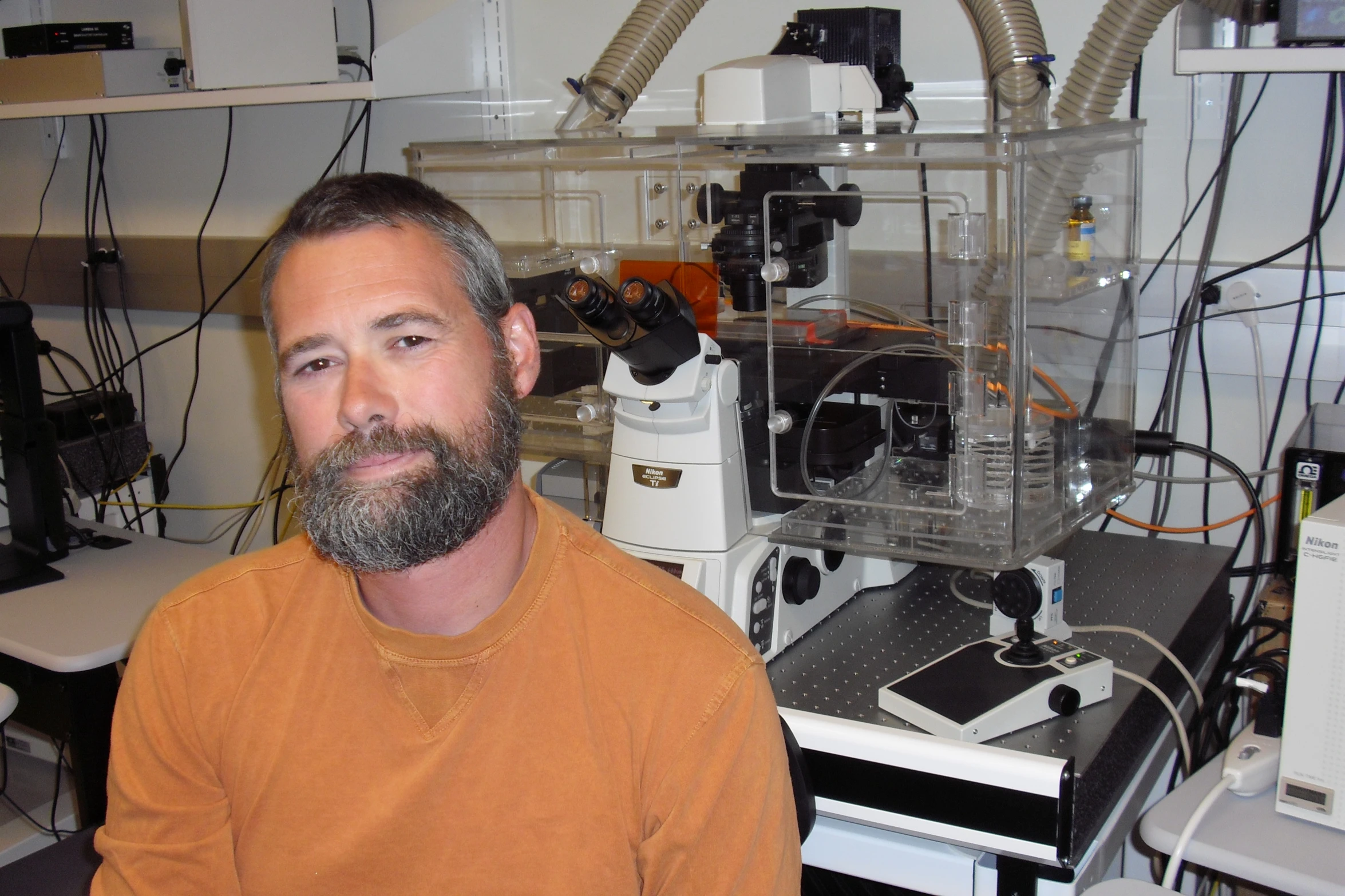 a man in an orange shirt sitting in a lab