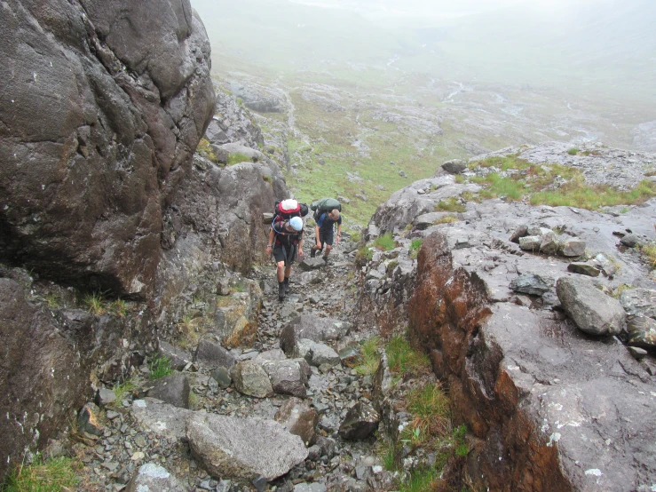 two hikers hiking up an old mountain in a foggy weather