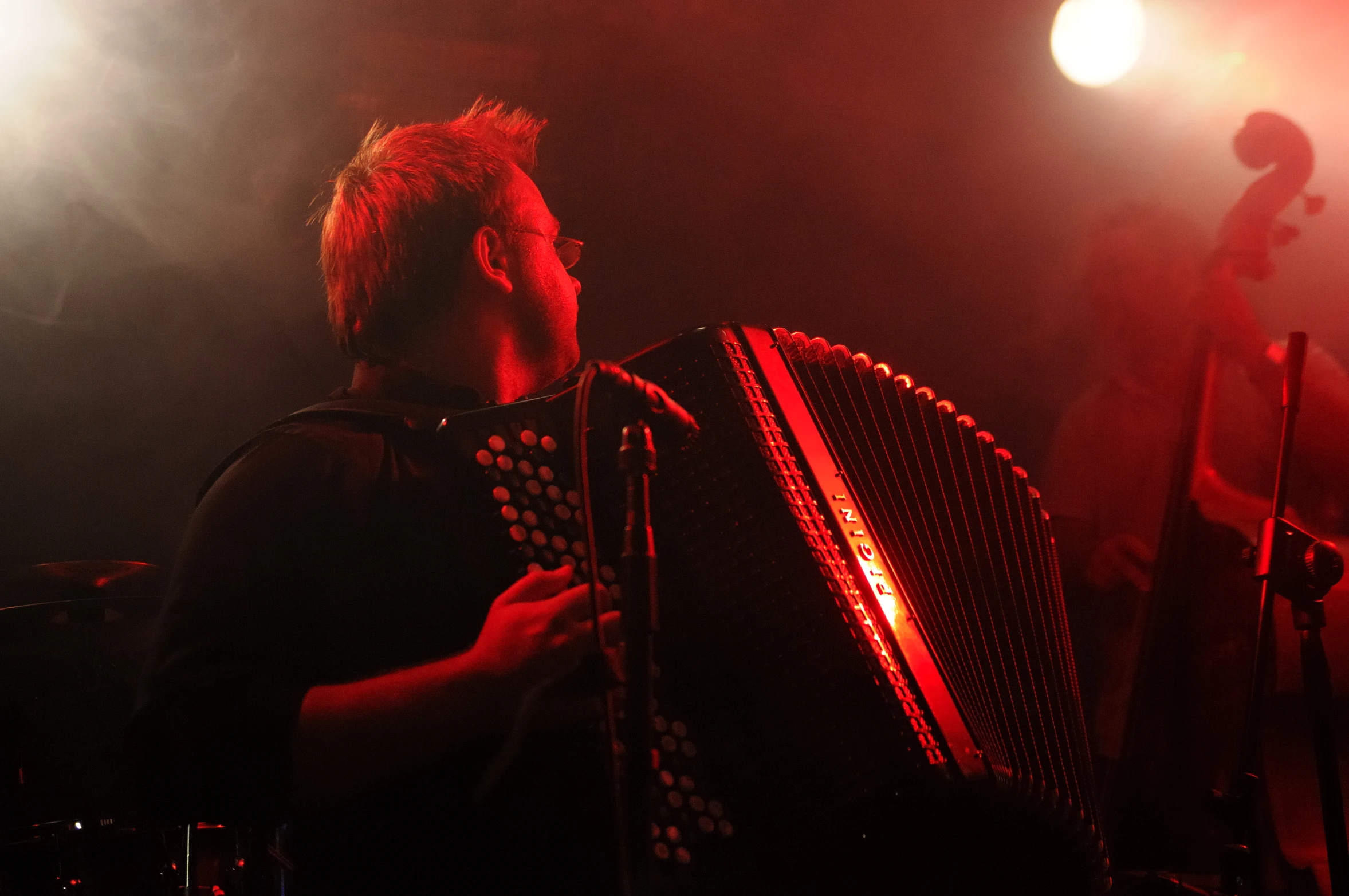 the man is playing an accordion in front of the stage lights