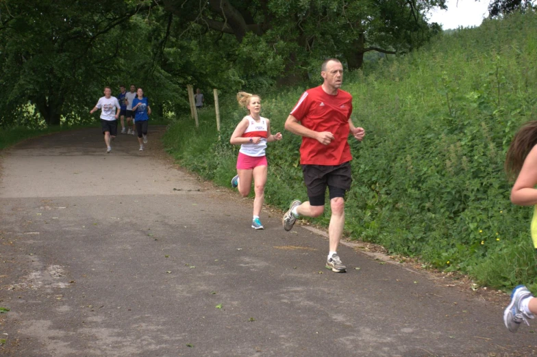 people are running down a trail with trees in the background