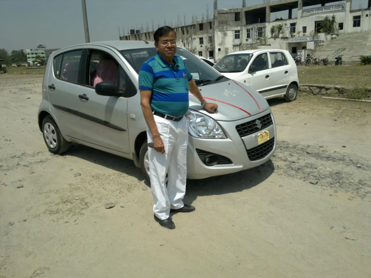 a man posing in front of his car