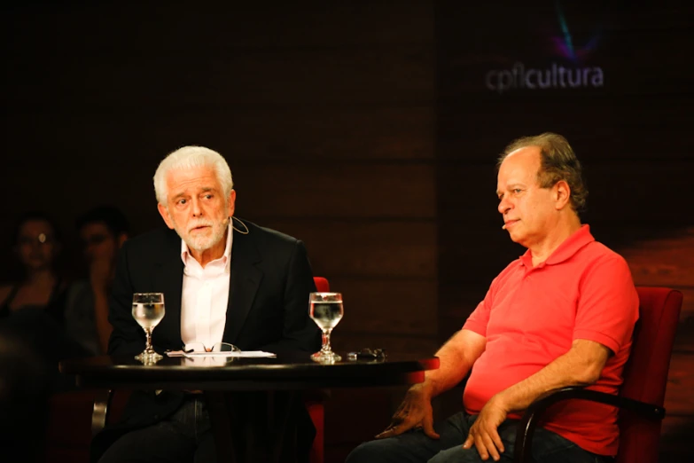 two men sitting at a table having wine