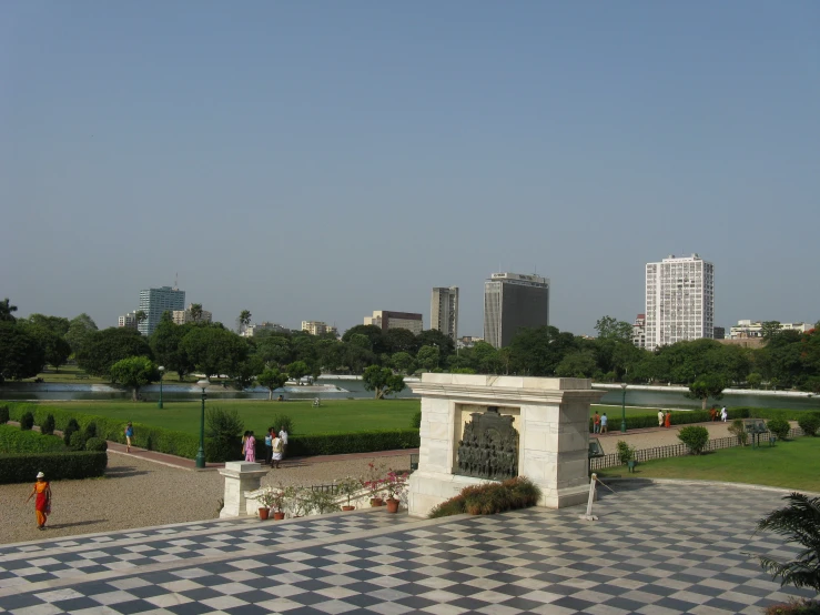 a checkered tile floor near a park with people standing and sitting