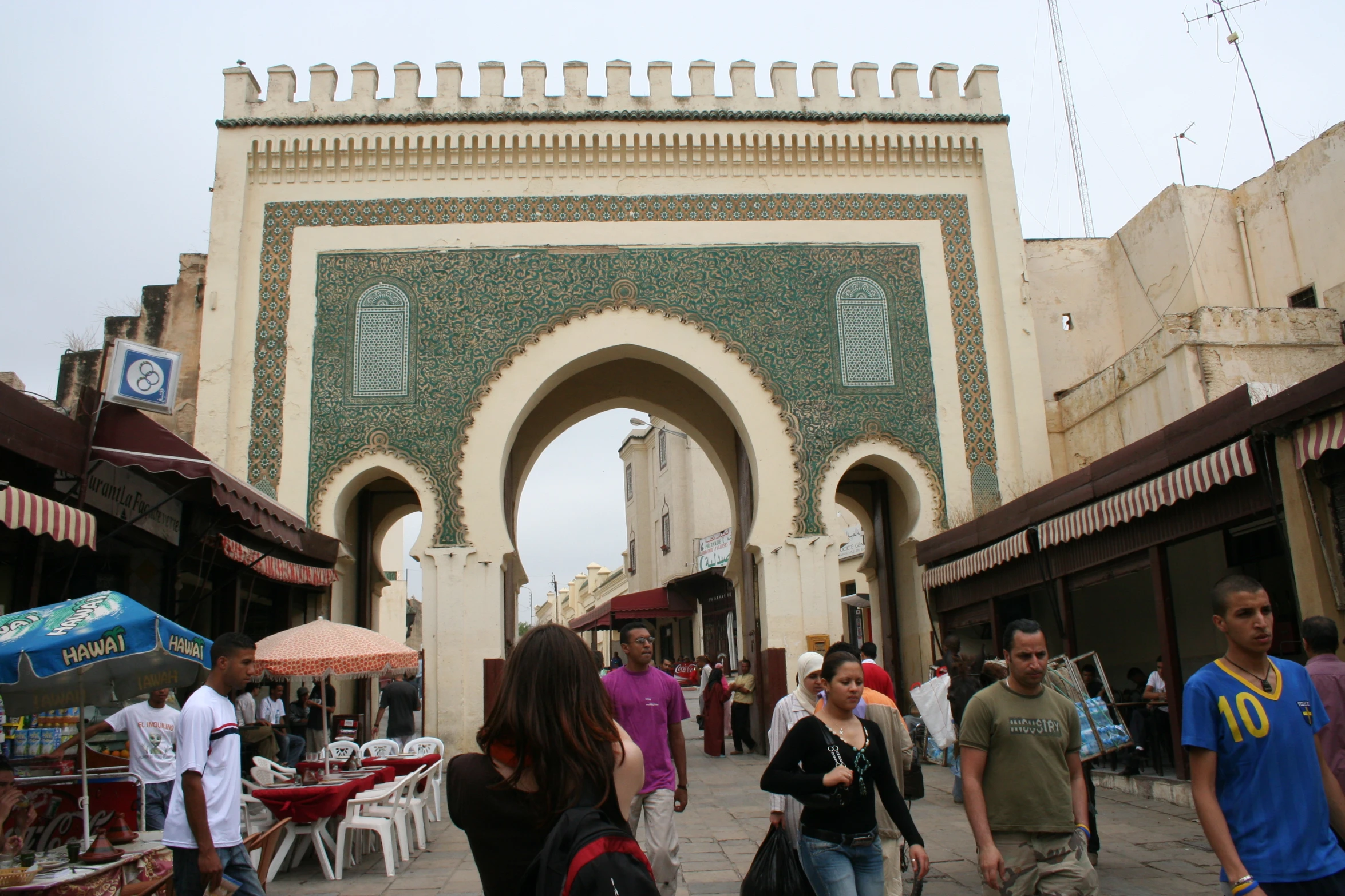 several people walk through a stone arch on a street