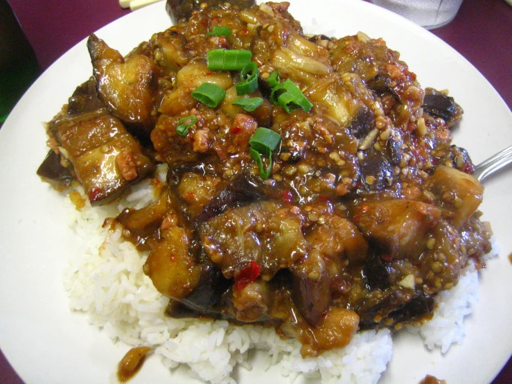 a white plate filled with chinese food on top of a purple table