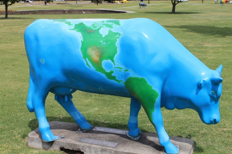 a large blue cow statue sitting in the grass