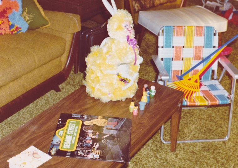 a fluffy yellow stuffed bunny sitting on top of a wooden coffee table