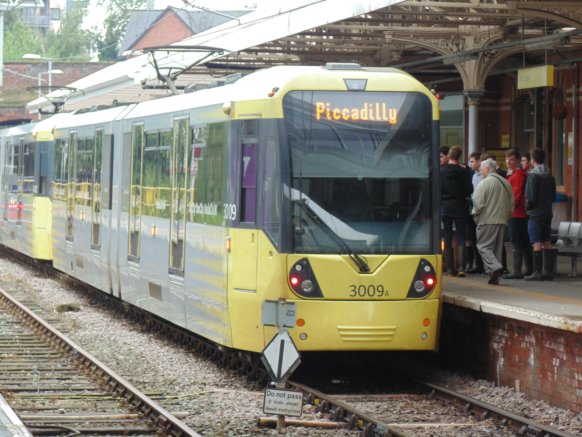 several people standing at the side of a train track